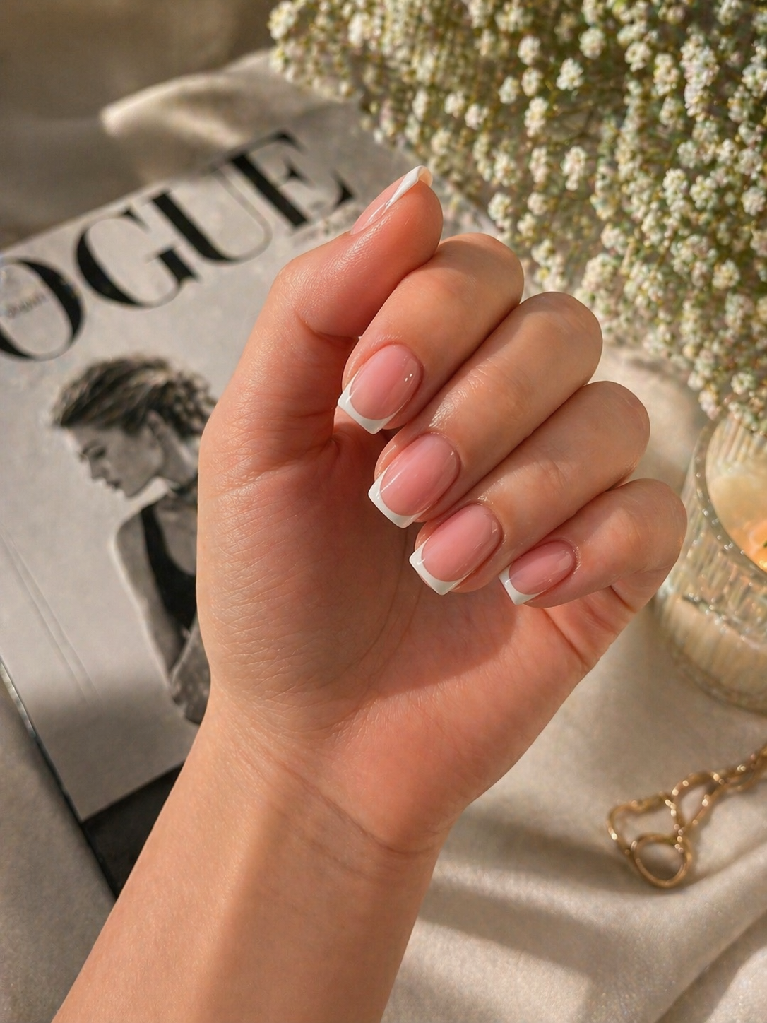 Natuurlijke French nagels naast een tijdschrift en gipskruid